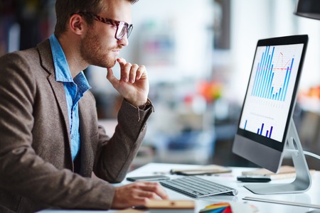 Male office worker looking at computer screen with data