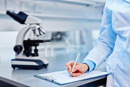 Young chemist making notes in labの写真素材