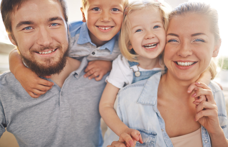 Happy family of parents and two children looking at camera