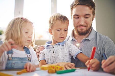 Young man drawing with his son and daughterの写真素材