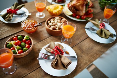 Glasses with juice, vegetables, nuts and plates with napkins and silverwareの写真素材