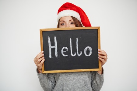 Young girl in Santa cap looking at camera out of blackboardの写真素材