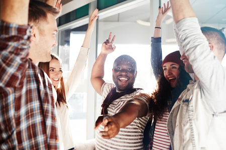 Ecstatic teens in casualwear keeping their arms raisedの写真素材