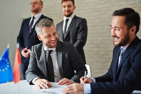 Cheerful businessmen sitting at the table and laughing during a meeting