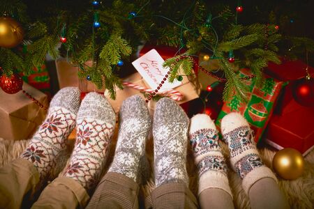 Feet of man, woman, and child in socks by Christmas treeの写真素材