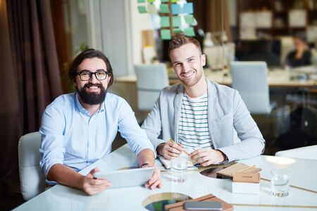 Two young businessmen looking at camera with smilesの写真素材