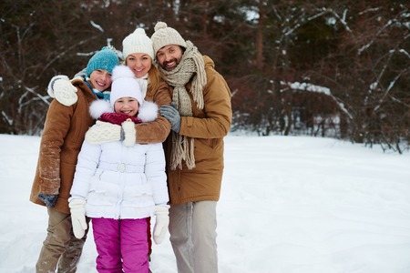 Happy family of four looking at camera in winter park