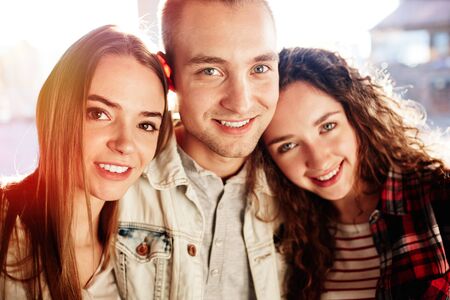 Three teenage friends looking at camera with smilesの写真素材