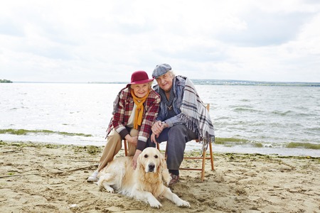 Two pensioners resting by seaside with their petの写真素材