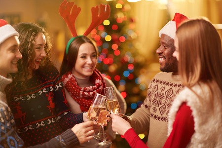 Happy friends toasting with bubbly champagne on Christmas eveの写真素材