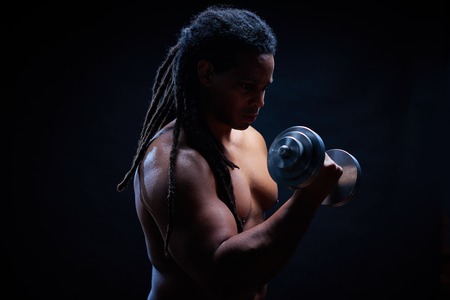 Muscular man with dreadlocks exercising in gymの写真素材