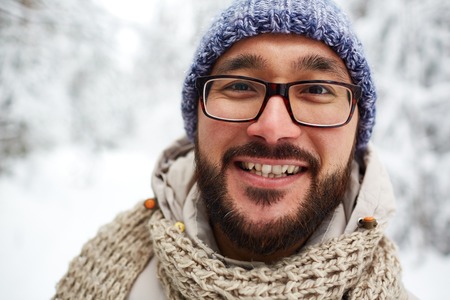 Happy Asian guy in winterwear looking at camera outsideの写真素材