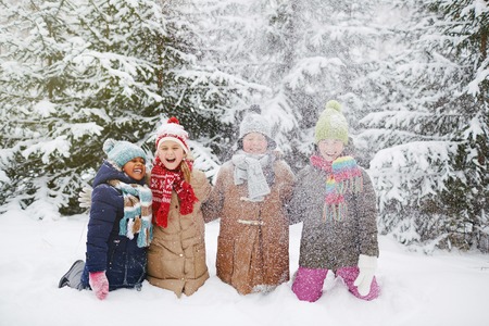Cheerful friends having fun in snow in winter parkの写真素材