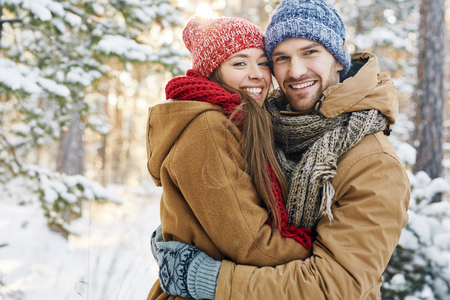 Embracing dates in winterwear looking at camera in natural environmentの写真素材