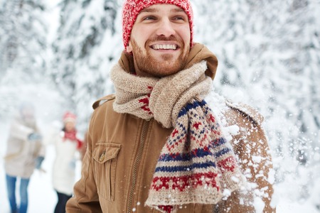 Happy guy in winterwear on background of his friendsの写真素材