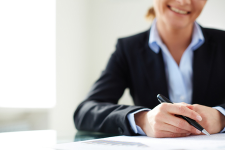 Businesswoman with pen over documentsの写真素材