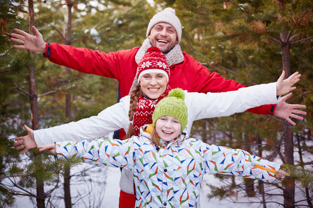 Smiling family of three posing outdoors in winterの写真素材