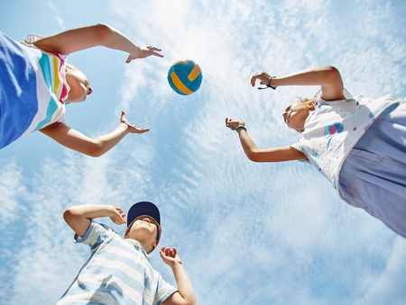 View from below of kids playing ballの写真素材