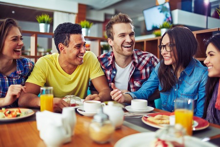 Happy teens talking during lunch in cafeの写真素材
