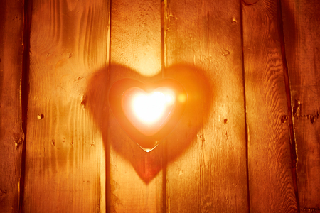 Burning heart-shaped candle on wooden backgroundの写真素材