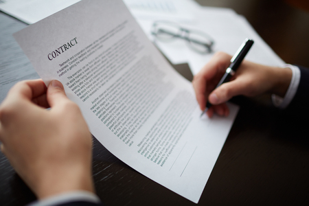 Close-up of male hands signing a contract with pen