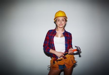 Young female in helmet holding hammer