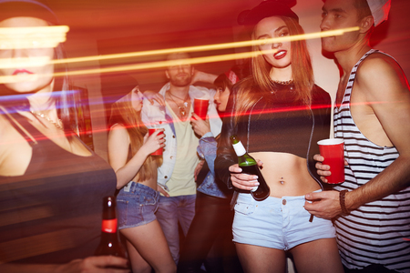 Young people with drinks relaxing at party in barの写真素材