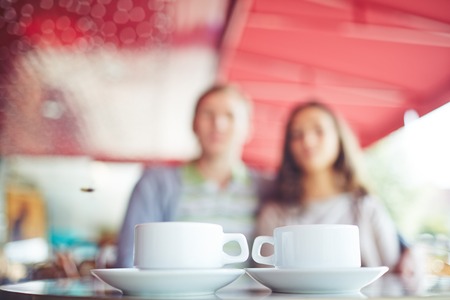 Two cups of coffee at the table with couple behindの写真素材
