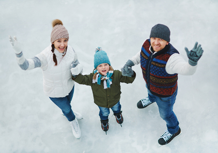 Family portrait of three people in skating rinkの写真素材