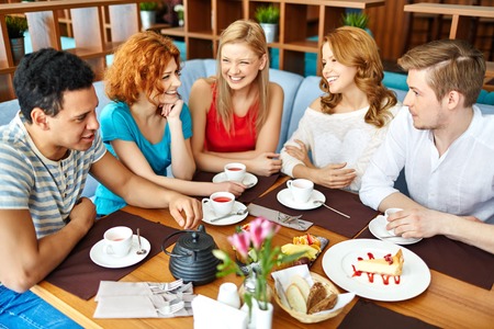 Group of friends communicating and drinking coffee with cakesの写真素材