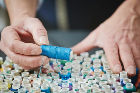 Tailor choosing threads for sewing clothesの写真素材