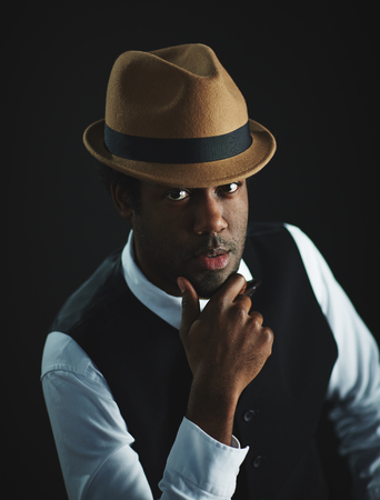 Elegant man in hat looking at cameraの写真素材