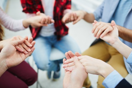 Circle of groupmates holding by hands at psychological sessionの写真素材