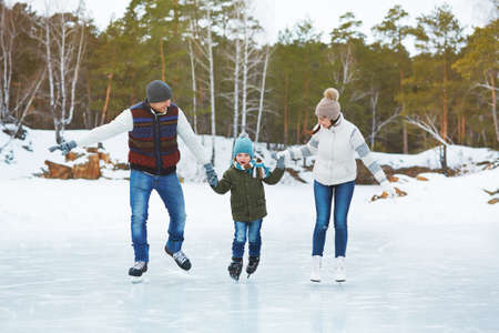 Happy parents with son skating on the rinkの写真素材