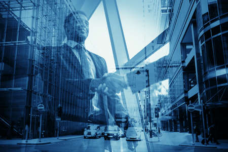 Confident businessman handshaking with partner and street of modern city