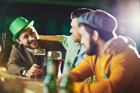 Friendly men drinking beer and talking in pub
