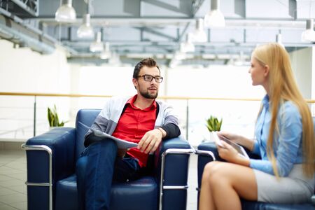 Two co-workers discussing plans in officeの写真素材