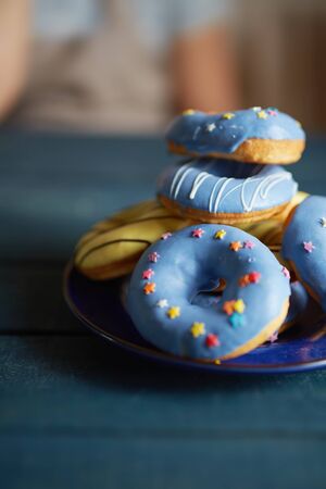Heap of doughnuts with blue icing and decorative stars on plateの写真素材