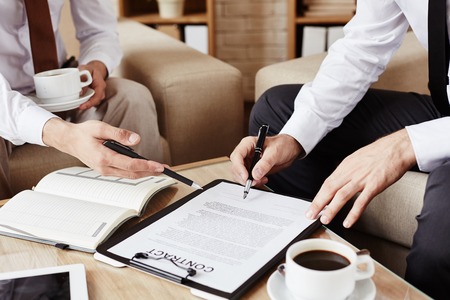 Male employees pointing at contract while discussing termsの写真素材