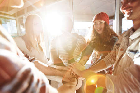 Friendly teenagers making pile of hands