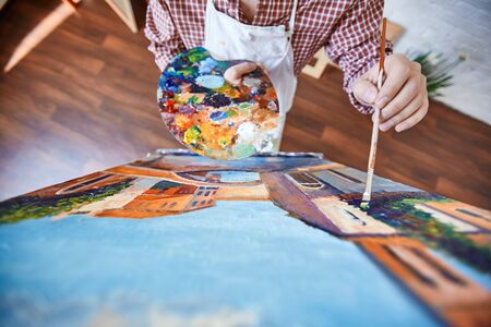 Artist with brush and palette painting a pictureの写真素材