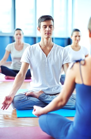 Young man meditating in yoga classの写真素材