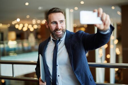 Businessman in black suit using a mobile phone for a video call with partnersの写真素材