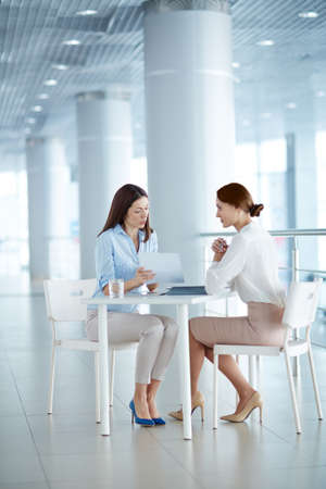 Two young colleagues discussing business contract in modern officeの写真素材