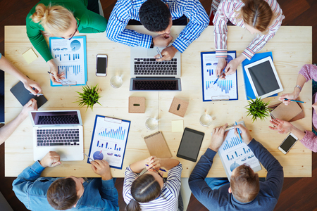 Above view of business team sitting around table and workingの写真素材