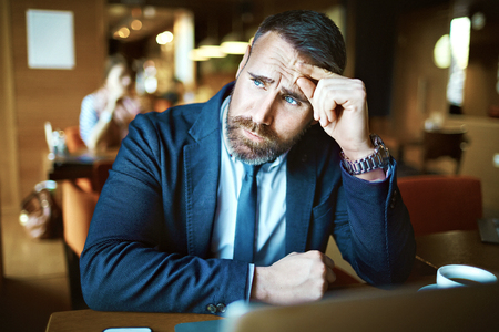 Pensive man touching his forehead and looking sidewaysの写真素材