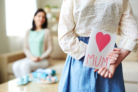 Girl holding card with red heart for her motherの写真素材