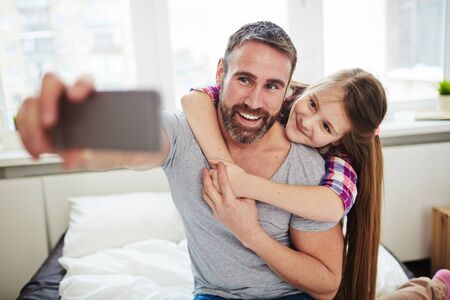 Teenage girl embracing her father for selfieの写真素材