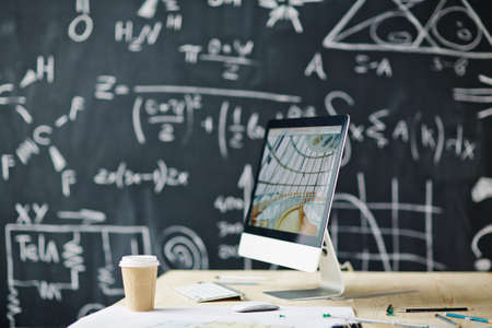 Computer on the table with blackboard in the background