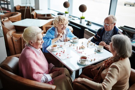 Group of friendly seniors playing lotto in cafeの写真素材